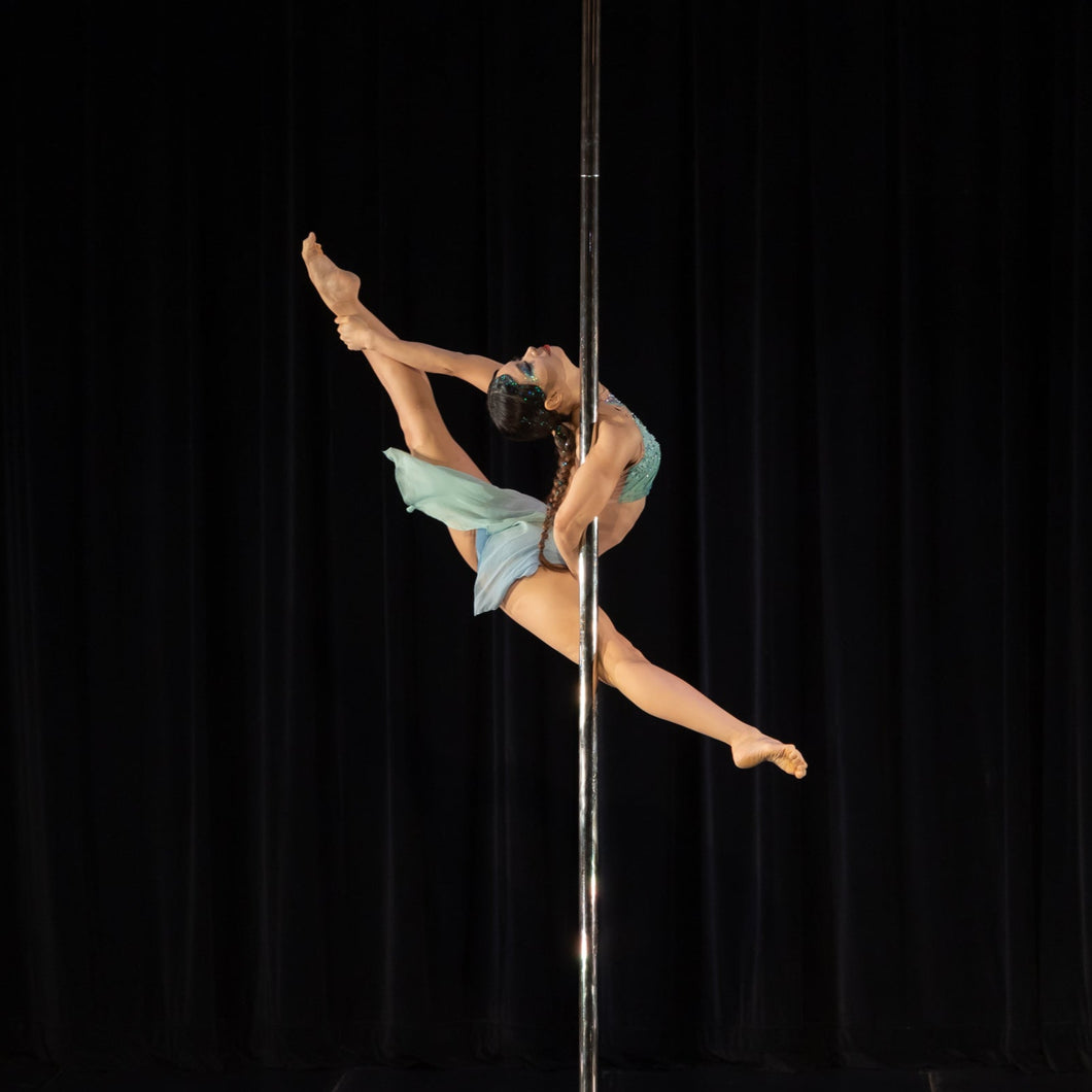 Person performing a pole dance move against a black curtain